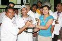 Devi Paul presents the winner’s trophy to captain of the Floodlights XI Mohan Boodraj as other team members look on.