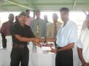 Lt. Kirk Marlock of the Guyana Defence Force (GDF) receives a box of the balls from secretary of the Georgetown Cricket Association (GCA) Shalim Baksh whilst other GCA executives and club members looks on.