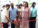 Roberto Thomas cuts the ribbon to open the Lusignan Nursery School yesterday with the assistance of Minister of Local Government, Kellawan Lall. Minister Shaik Baksh is at left and Head Teacher of the school, Evelyn Kendall is second from right.