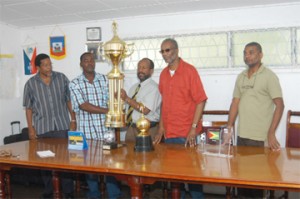 President of the Guyana Football Federation (GFF) Colin Klass, third from right, hands over the championship trophy to GFF vice-president, Franklyn Wilson.  Others in picture are from left, Noel Adonis, secretary of the GFF, Odinga Lumumba, president of Alpha United and Frederick Granger,  Public Relations Officer of the GFF. Aubrey Crawford photo)