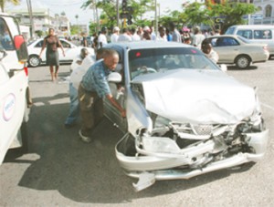 Public–spirited citizens assist to move the taxi which the minibus slammed into before toppling over.  The car was almost halfway across Middle Street heading south. (Photo by Jules Gibson)