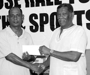 Assistant organizing secretary of Rose Hall Town Youth and Sports Club Ravindranauth Kissoonlall left, receives the cheque from Basil Butcher in whose name the Trust Fund has been established. (Clairmonte Marcus photo)