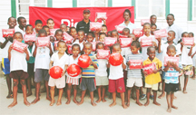 Boys at the St John Orphanage smile as they display their Digicel radio lunch packs and footballs as Digicel Guyana Sponsorship Executive Shirwin Campbell and Orphanage Administrator Grace Daniels look on.  