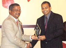 Minister of Culture, Youth and Sport, Frank Anthony (right) presents the award for Business Excellence on HIV/AIDS in Advocacy and Individual Leadership to Jagnarine Singh, General Manager of Guyana Rice Development Board (GRDB). GRDB also won the award for core competency. 