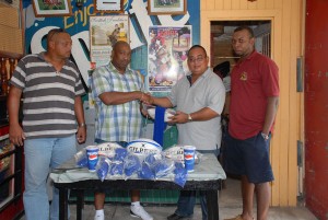  President of the Pepsi Hornet Rugby Club, Peter Green, second from right, receives the hoses and practice balls from Cleon Baxter-Dennis. At left is Peter Campayne and, at right, Alton Agard.