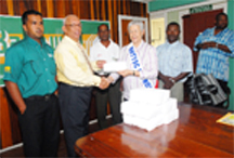 Marketing Executive Maurice Robello (L) hands over the cheque of $170,000 to Patron of RHTY&SC June Mendes (R) as assistant marketing executive Raymond Seelall (far left), Rabindranauth Kissoonlall and assistant secretary Franklin Ross and Secretary Hilbert Foster (far right) look on. (Clairmonte Marcus Photo)  