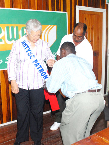 In this Clairmonte Marcus photo,  Assistant Secretary, Rose Hall Town Youth and Sports Club Franklyn Ross and Assistant Organizing Secretary, Rabindranauth Kissoonlall, pin the sash of patron on Mrs. June Mendes, yesterday.