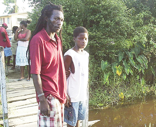 Roydon Daniels (left) with Prince Gardner, who both jumped into the canal to try to save the two boys yesterday.  The area where the boys went under is at right.