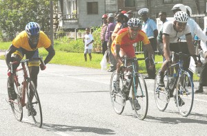 Defending champion Alonzo Greaves (centre) along with John Charles (left) and Darren Allen (right) all grimace as they go past the finish line in the Guyana Cycling Federation road race held yesterday morning. (Clairmonte Marcus photo)