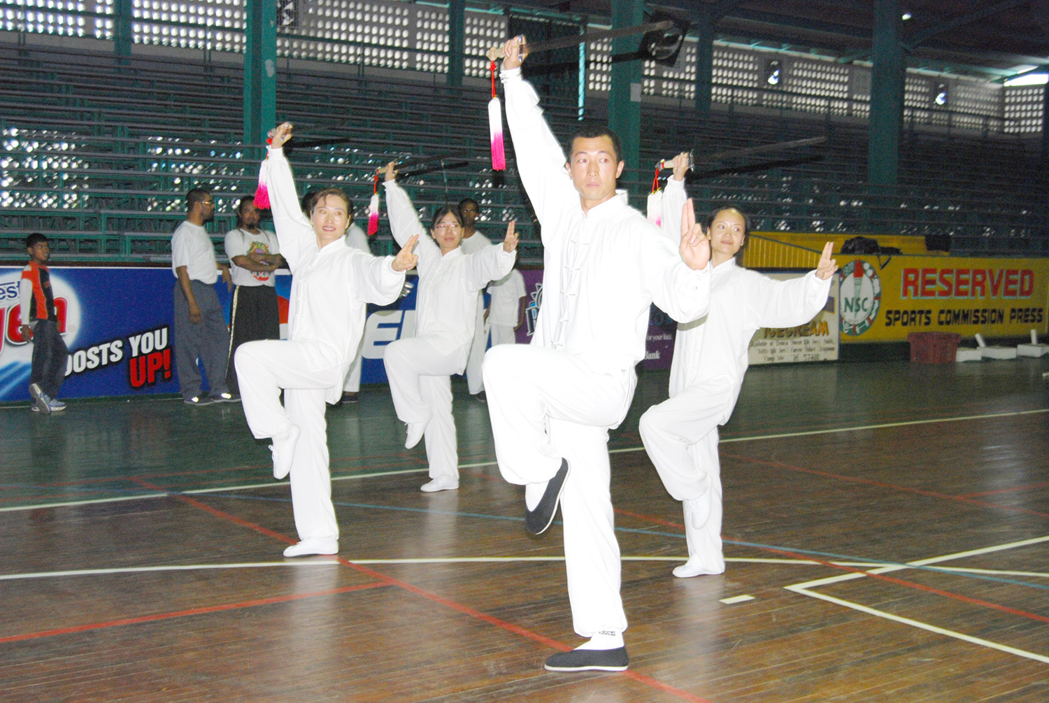 Local Tai Chi Instructor Cao Aibing, front right, demonstrates one of the forms in the art of the Tai Chi sword along with Wang Jin, wife of the Chinese Ambassador, front left, and two secretaries attached to the Ambassador Sun Liping (rear left) and Huang Shang Shang (rear right) at the Cliff Anderson Sports Hall yesterday. (Lawrence Fanfair photo)