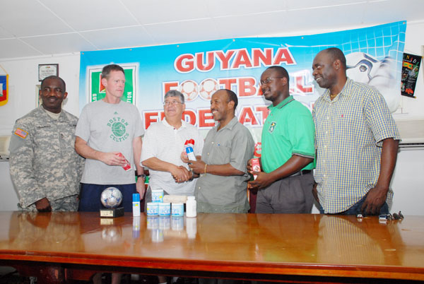Colonel Matthew Ridge (third from left) hands over one of the medical supplies to president of the Guyana Football Federation (GFF) Colin Klass, as from left, SFC of the US Army Hilliman, Colonel Charles Ware, general manager of the Guyana team Aubrey Hudson and Organizing Secretary of the GFF Aubrey ‘Shanghai’ Major look on admiringly. (Clairmonte Marcus photo)