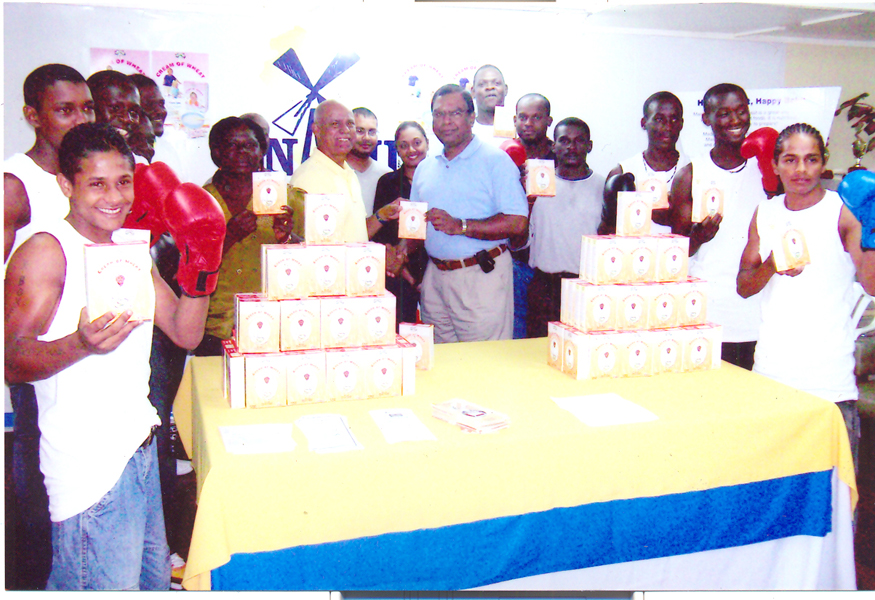 Chief Executive Officer (CEO) NAMILCO Bert Sukhai hands over a box of the Cream of Wheat cereal to President of the Guyana Amateur Boxing Association (GABA) Afeeze Khan, as staff members of NAMILCO along with the six boxers look on.