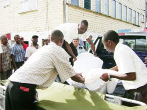 The body of one of the two men shot dead by the police at Goat Farm, Region 10 being loaded on to a stretcher at the Ogle Airport yesterday. 