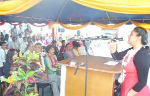 Minister of Human Services & Social Security, Priya Manickchand addressing the gathering. Seated in the front row at left is attorney-at-law, Yogini Lochan (behind plant). 