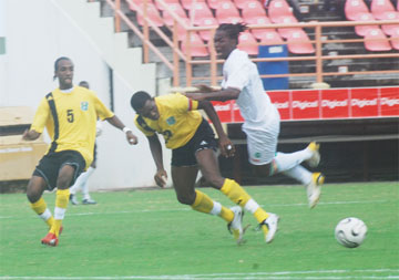 Skipper Charles ‘Lily’ Pollard ensures this Surinamese striker does not proceed any further even as his teammate Walter ‘Boyd’ Moore gets ready to offer assistance. This was  part of the action between Suriname and Guyana at the national stadium yesterday which the former won 2-1. (Lawrence Fanfair photograph).