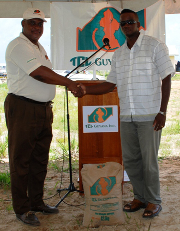 TGI Plant Manager Mark Bender (left) making a symbolic handing over of cement to home partner Randolph Lafleur.