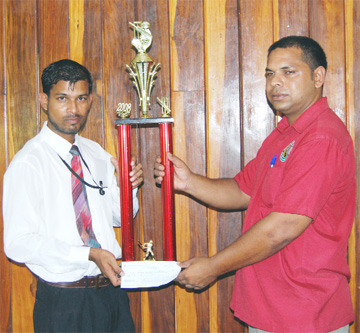 Managing Director Rising Sun Farms Reard Shivrattan hands over the championship trophy and sponsorship cheque to Marketing and Public Relations Officer West Berbice Cricket Association (WBCA) Abel Seetaram. (Lawrence Fanfair photo) 