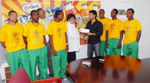 Chief Executive Officer (CEO) Ansa McAl, Beverly Harper, hands over the cheque to Faizal Khan, committee member of Guyana Friends and Family Football Fund,  as members of the Golden Jaguars along with Troy Cadogan look on.