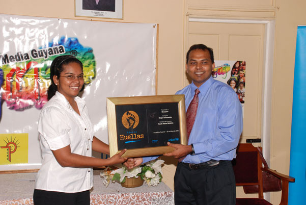 Vidya Brijlall receiving the ’Traces’ award from Minister of Culture, Youth and Sport, Dr. Frank Anthony.