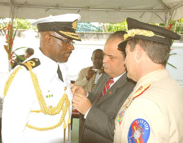 Venezuelan Ambassador Dario Morandy Figuera (centre) pins the Medal Star of Carabobo on GDF Chief of Staff, Commodore Gary Best at the Venezuelan Institute for Co-operation and Culture yesterday. Looking on is Sergeant, Bolivarian National Army, Rafael Cabrera. (Jules Gibson photo)