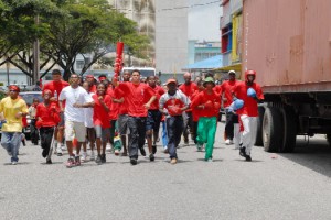 The lone locally-based Olympian Niall Roberts carries the symbolic Olympic torch during the final leg of the Coca Cola Caravan which started at the Providence National Stadium and finished at the Main Street Quik Serv Outlet, yesterday.  
