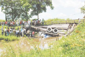 Rescuers trying to lift Imran Hassan out from under the truck. The chain visible in the photo is attached to the front end loader which pulled at the truck to afford the men space in which to work. (Jules Gibson photo)