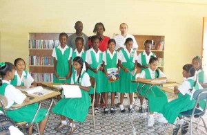 Standing with students (from right to left) are Colin Persaud, acting headmistress Constance McCalmont and Clayton Britton while other students read some of the books from the donation. 