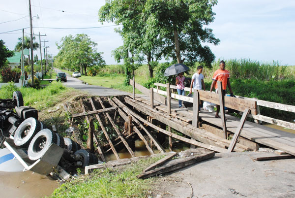 Treading carefully: Residents on Tuesday using the temporary walkway the NDC tacked together with pieces of wood from the broken bridge. 