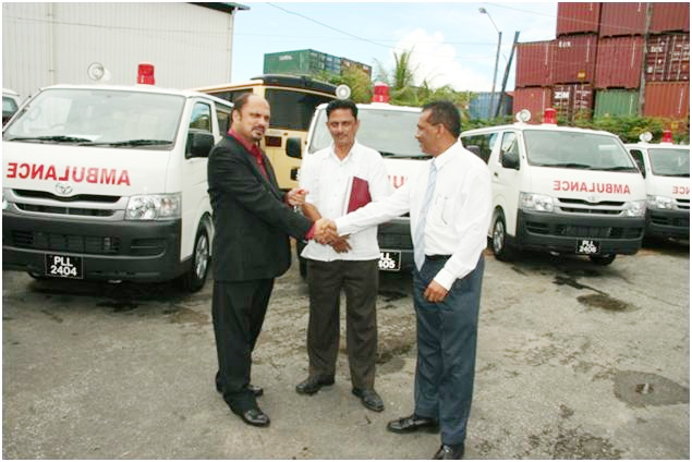 Minister within the Ministry of Health Dr Bheri Ramsaran (left) receives the keys for the ambulances from a sales representative while Permanent Secretary in the ministry Hydar Ally (centre) looks on. 