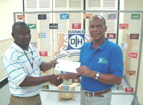 Troy Peters, Banks DIH Communications Manager presents the cheque to Clairmont DaSouza, Assistant Secretary Treasurer of the Guyana Boxing Board of Control.