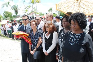 From right, Arthur Chung’s son, Raymond, wife Doreen and daughter Diane standing among the grief stricken yesterday, a few feet from his casket which was at the Seven Ponds. (Jules Gibson photo)