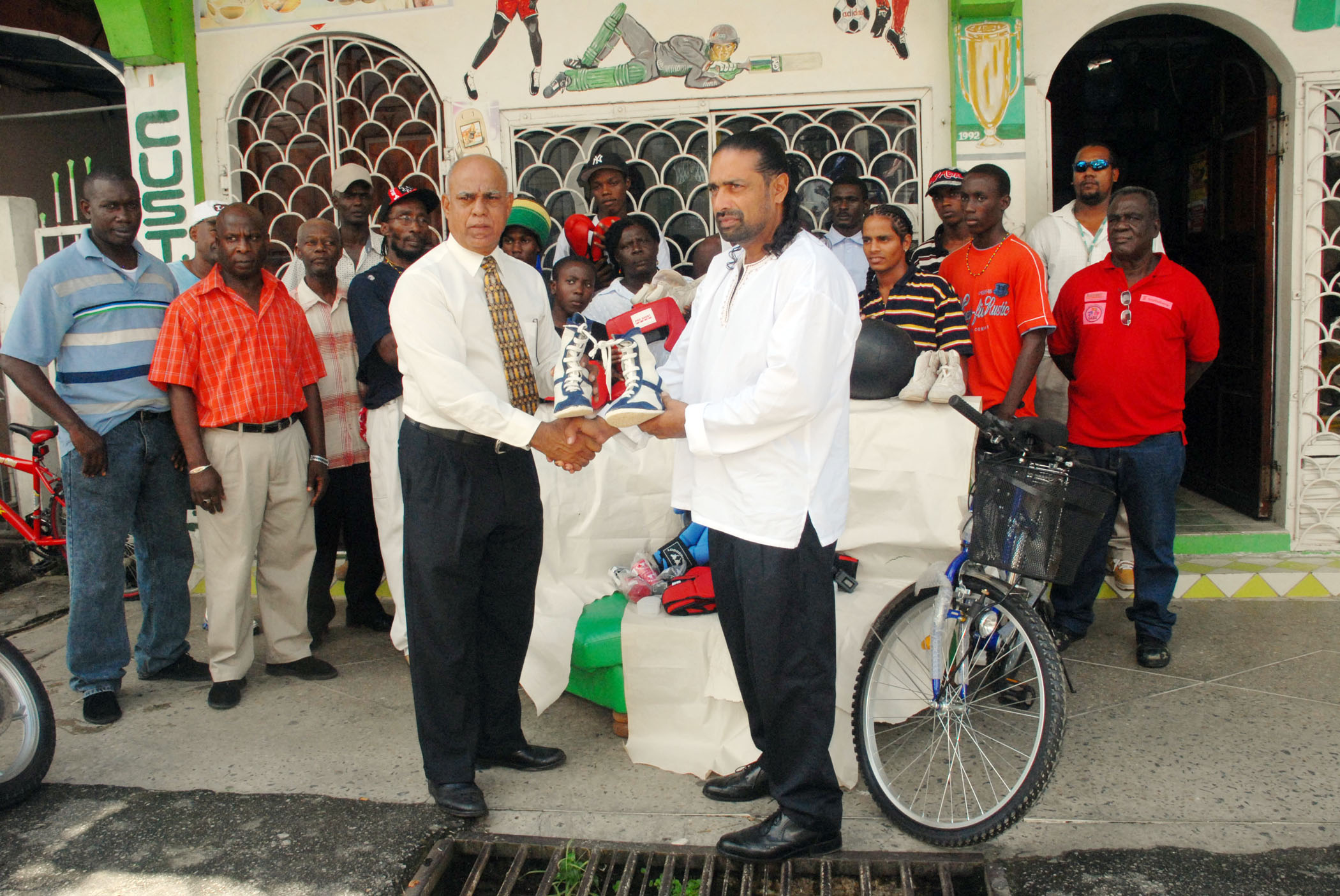 Managing Director of West Indian Sports Complex, Mohammed Feroze Khan, right, hands over a pair of boxing shoes to President of the Guyana Amateur Boxing Association (GABA) Affeeze Khan in the presence of members of the various boxing gyms. (Clairmonte Marcus photo)