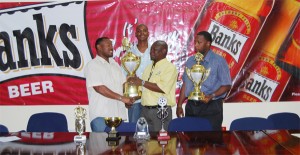 Troy to Troy: Banks DIH Limited Communications Officer Troy Peters hands over the Banks Beer trophy to president of the Georgetown Football Association (GFA) Troy Mendonca even as Outdoor/Special Events manager Banks DIH Limited, Mortimer Stewart, and Technical Assistant (GFA) Lyall Gittens look on. (Lawrence Fanfair photo)