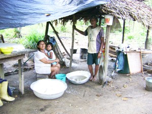 In camp: Daniels Matthews, his wife, Betty and a grandchild at their farmhouse. A tub of grated cassava for making cassava bread is next to Betty. 