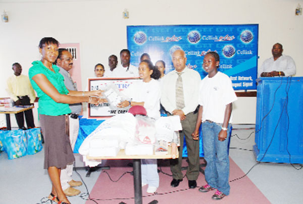 Avia Lindie manager of Metro Berbice branch, hands over the cricket gear to a member of the Rose Hall Town Youth and Sports Club/ Metro Office Supplies female team as other members of the team look on. Partly hidden at left is Roy Darson marketing Manager Metro whilst Taejnauth Jadunauth CEO Metro is second from right. (Clairmonte Marcus photo)
