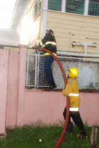 Looking for every angle: These firemen were working hard yesterday morning to find the right angle to tackle the flames that engulfed the buildings housing the psychiatric wards. (Jules Gibson photo)