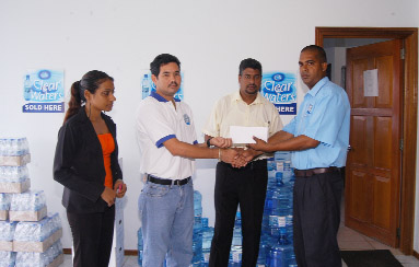 Gavin Gouveia receives his sponsorship cheque from Devanand Indar Operations Manager of Clear Waters Company whilst Managing Director Lloyd Singh (centre) looks on.