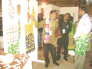 Artistic Director of the Surinamese contingent, Hank Tjon (left) explains the meaning of some of the pieces to Minister of Culture, Frank Anthony at the Umana Yana yesterday. Suriname’s Permanent Secretary of Culture, Sidoel Stanley (centre) watches on. 