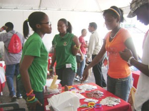 Wrap it up: Volunteers at the Ministry of Health booth at the Carifesta Youth Village, National Park handing out condoms to youths. (Iana Seales photo)