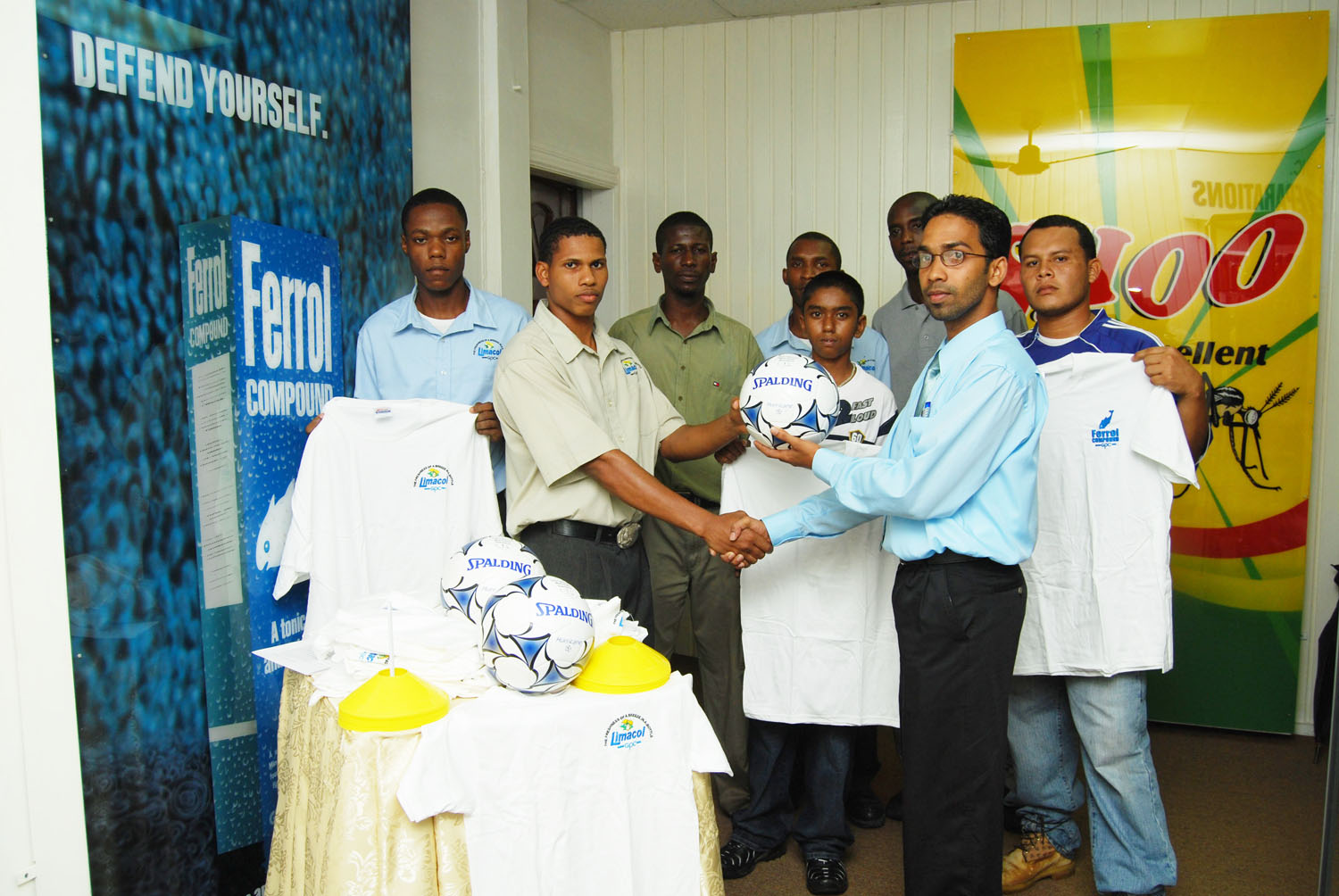 New GPC Inc. marketing manager Trevor Bassoo (2nd right) handing over one of the footballs to Crane Football Club captain Shemry Cox as president Vince Griffith (3rd left) looks on long with other club members with secretary Jevon Rodrigues at Extreme right.(Photo by Lawrence Fanfair)