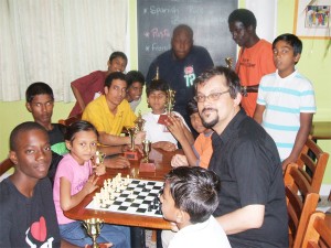 Flashback:  Former national chess player Tony Hanoman is surrounded by junior chess players from the Guyana Chess  Federation. Hanoman currently resides in Sweden, but returned to Guyana in August 2007 and sponsored a tournament for both junior and senior players. This year, Demerara Distillers Limited has undertaken to sponsor the tournament as a special Carifesta feature, with incentives in both categories. Play begins this morning at 10 am sharp at the Kei-Shar’s Sports Club in Hadfield Street.