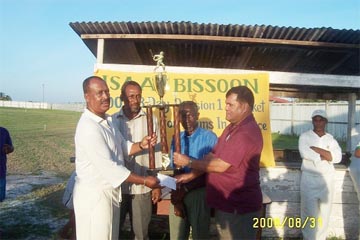 President of the Guyana Cricket Board (GCB) Chetram Singh presents the 2007 Isaac Bissoon champions trophy to captain of Young Warriors cricket team Hubern Evans. Looking on are Berbice Cricket Board of Control (BCBC) competitions committee chairman Carl Moore and former president of the BCBC Malcolm Peters  second right. 