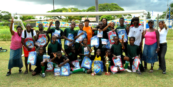 Champions Again!!! The Beacon United Football Club poses with itsprizes and Guyana Beverage Inc. Customer Representative Shameiza Yadram who stands at centre after they won their second consecutive Chubby Under-14 Football Championship at the Tucville Playfield on Saturday.