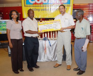 Liaison Officer of the `Reds’ Perreira Foundation, Troy Peters, (second left) receives the cheque worth US$400 from Purchasing and Customer Service Representative of Courts Guyana Inc. Clyde DeHaas while Marketing Executive of Courts Guyana Molly Hassan (L) and Vice President of the Guyana Cricket Board Malcom Peters look on.