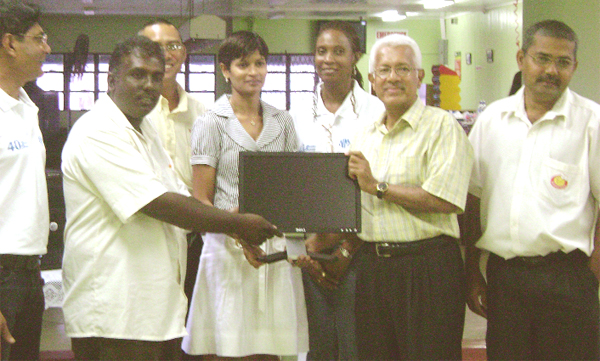 A representative of the Essequibo Islands Secondary School (left) receiving the computer system from Deo Persaud, Neal and Massy (Guyana) CEO. 