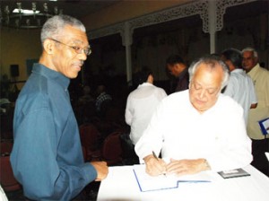  Sir Shridath Ramphal autographs a copy of Triumph for UNCLOS for Brigadier David Granger (ret). (Photo by Jules Gibson) 