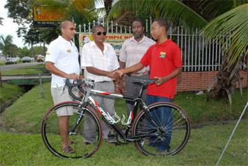 National cycling coach and race organizer of the Guyana Cycling Federation Hassan Mohammed (second left) hands over the cycle to Enzo Matthews in the presence of GCF president Hector Edwards (centre) and assistant racing secretary Malcolm Sonaram(left). (A Clairmonte Marcus photograph)   