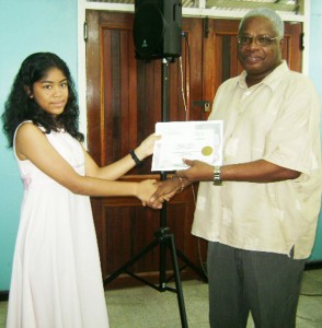 Region Ten’s top Grade Six Assessment performer, Angelica Holder, receives her certificate from Chief Executive Officer (CEO) of Linmine Secretariat, Horace Jones.