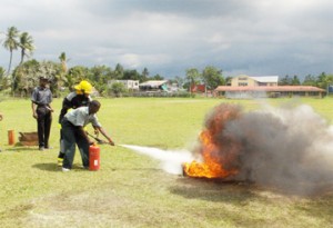 Student of the Diamond Special School Colin Sertimer putting out the fire guided by Fireman David Persaud. 