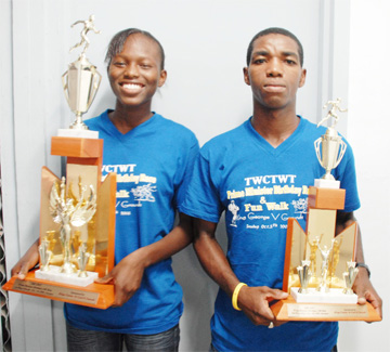 In this Clairmonte Marcus photo, Alika Morgan (L) and Kelvin Johnson (R) pose with their prizes they won in the Prime Minister’s Birthday 10K run in Antigua.  